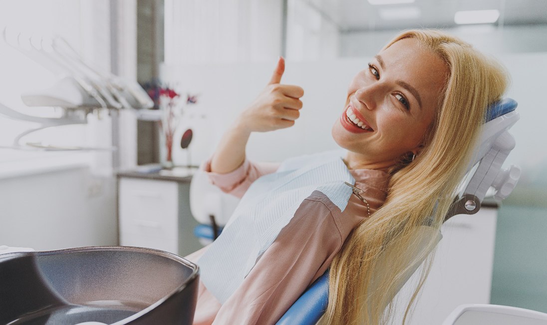 Female patient in dentist’s office giving a thumbs-up