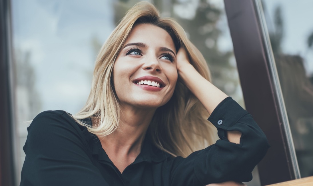 Blonde woman in window smiling after seeing her cosmetic dentist in Ramsey New Jersey