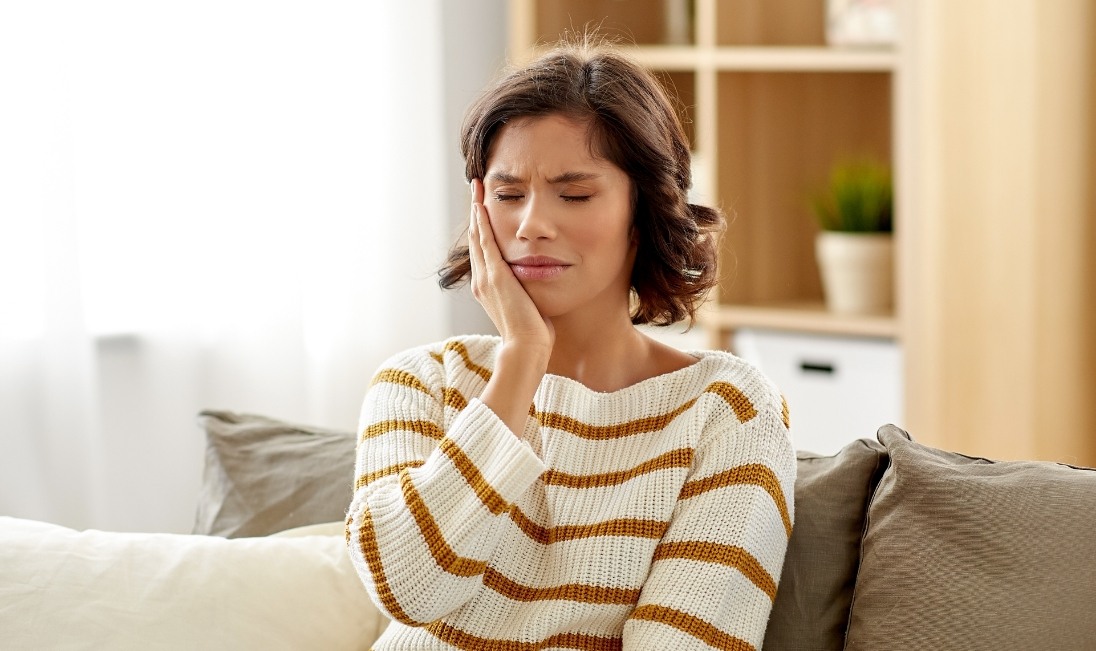 Woman who needs emergency dentist in Ramsey holding her cheek in pain