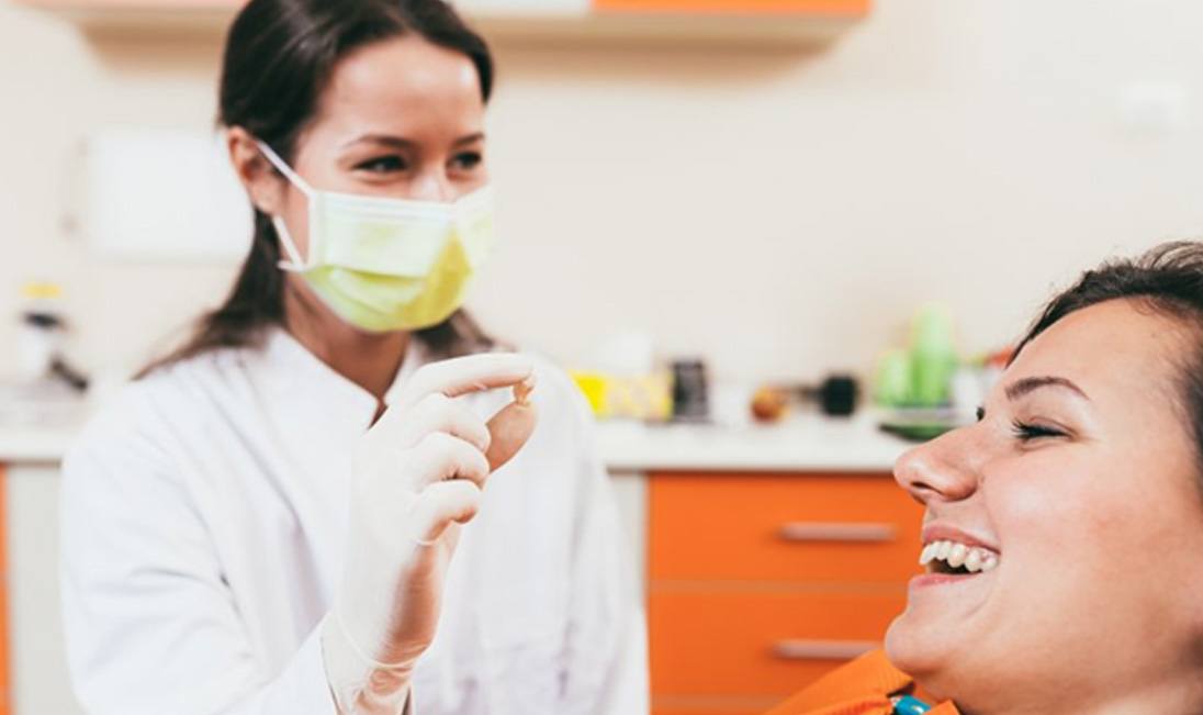 a dentist holding a patient’s tooth after extraction