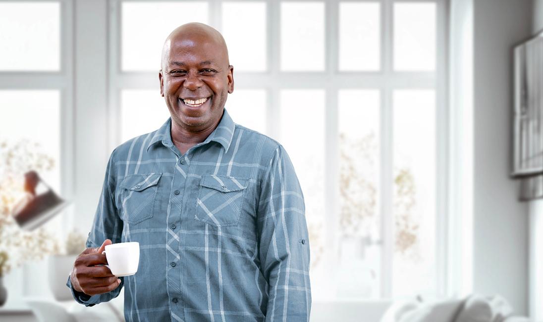 a man smiling and holding a cup of coffee