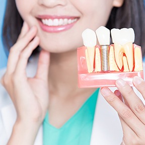 A dentist holding a model of a dental implant