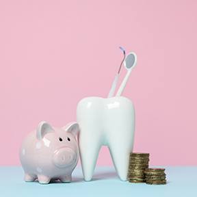 A piggy bank, model tooth, and coins against a pink background