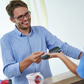 A young man paying the cost of dental implants