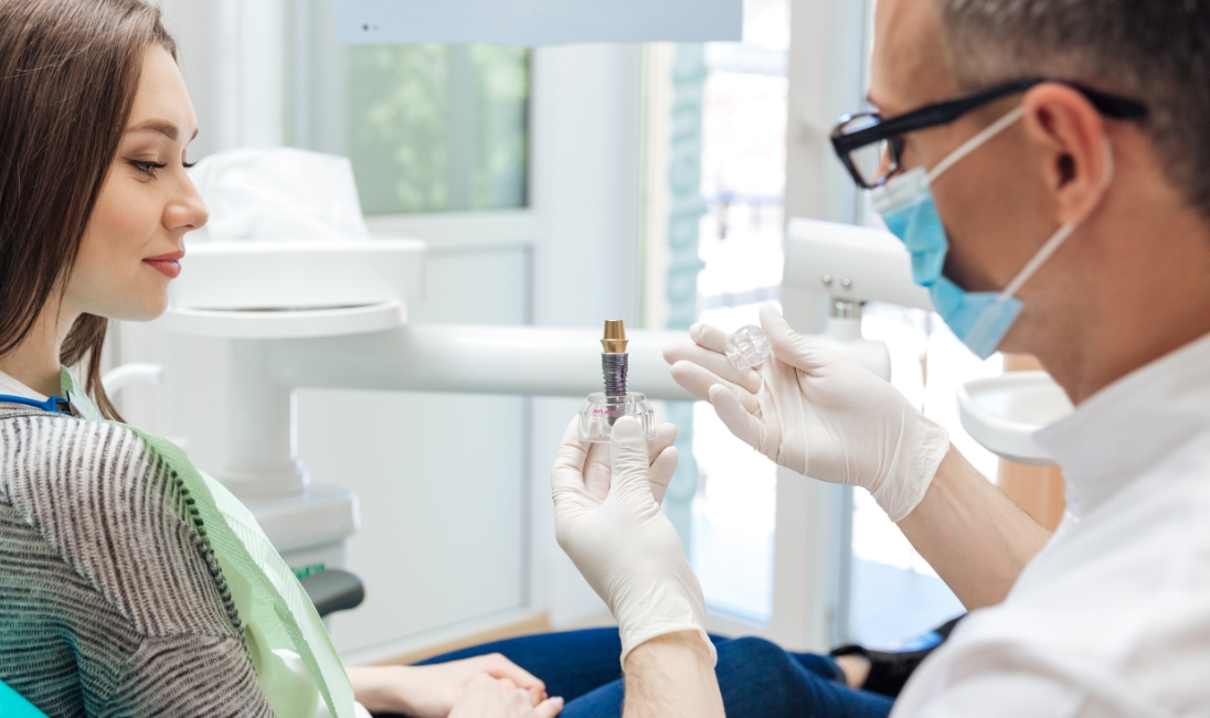 Dentist showing a young woman a dental implant