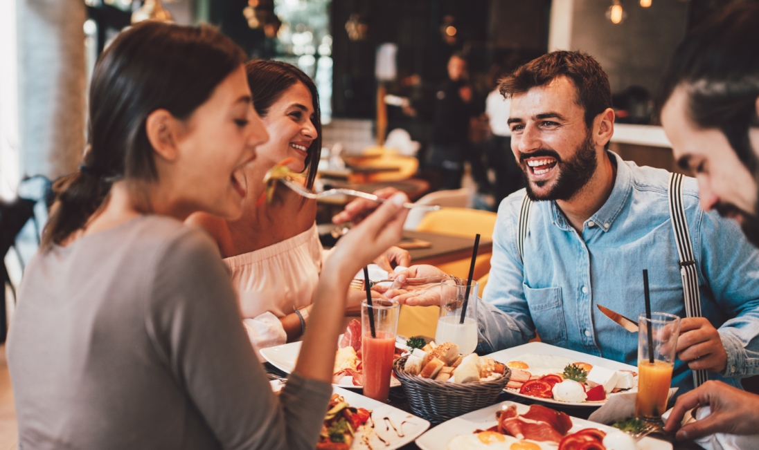 Group of people laughing while eating at a restaurant