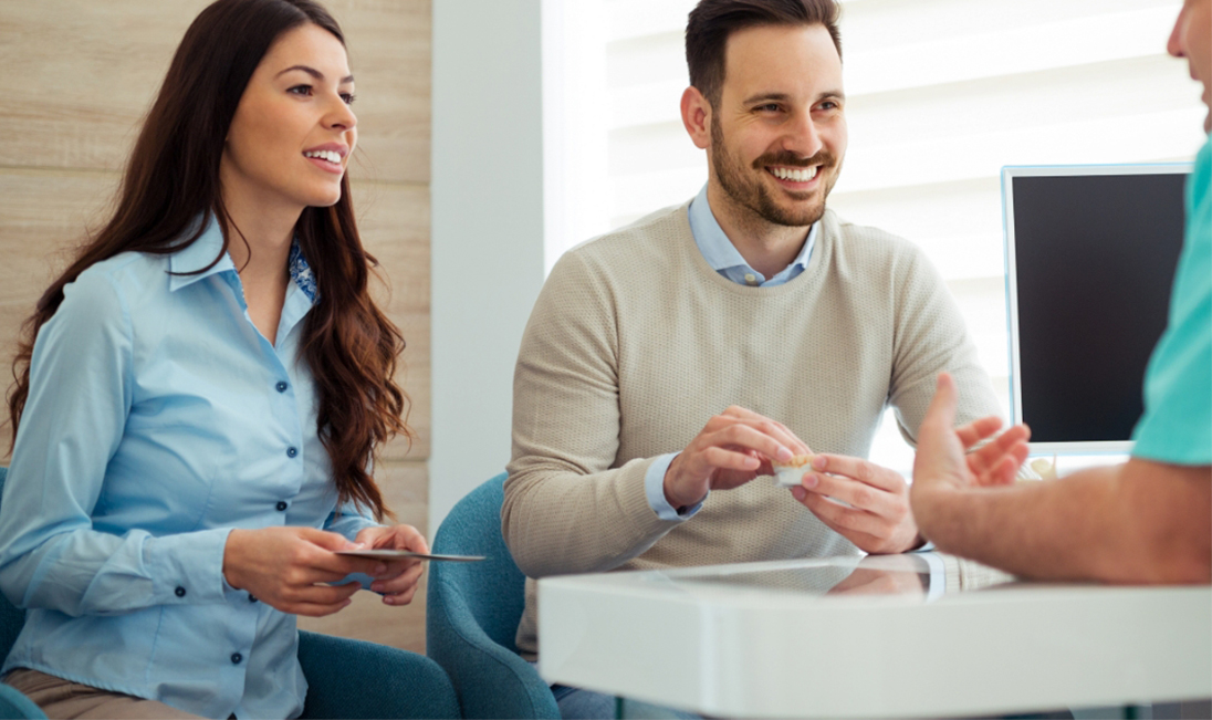 Man and woman discussing the cost of dental implants in Ramsey with dental team member