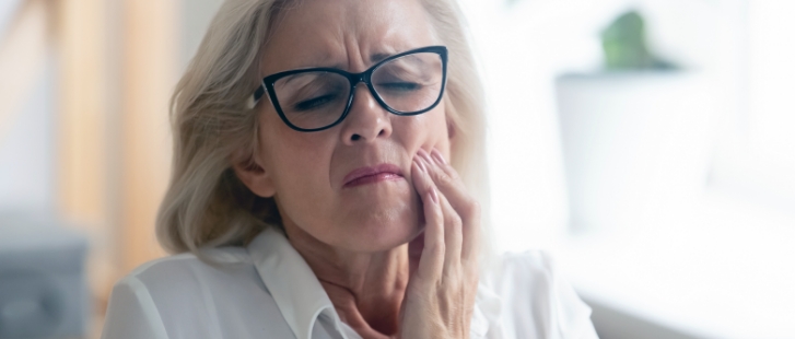 Senior woman holding her cheek in pain