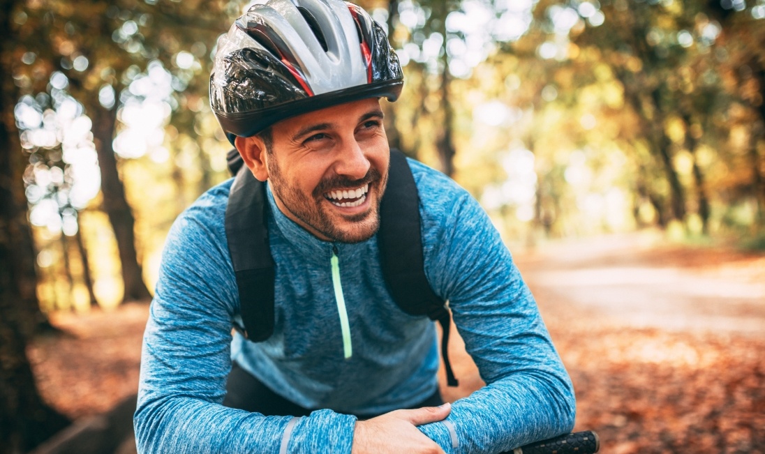 Smiling man riding a bike in the woods