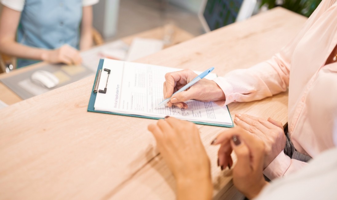 Person filling out a paper form on a clipboard