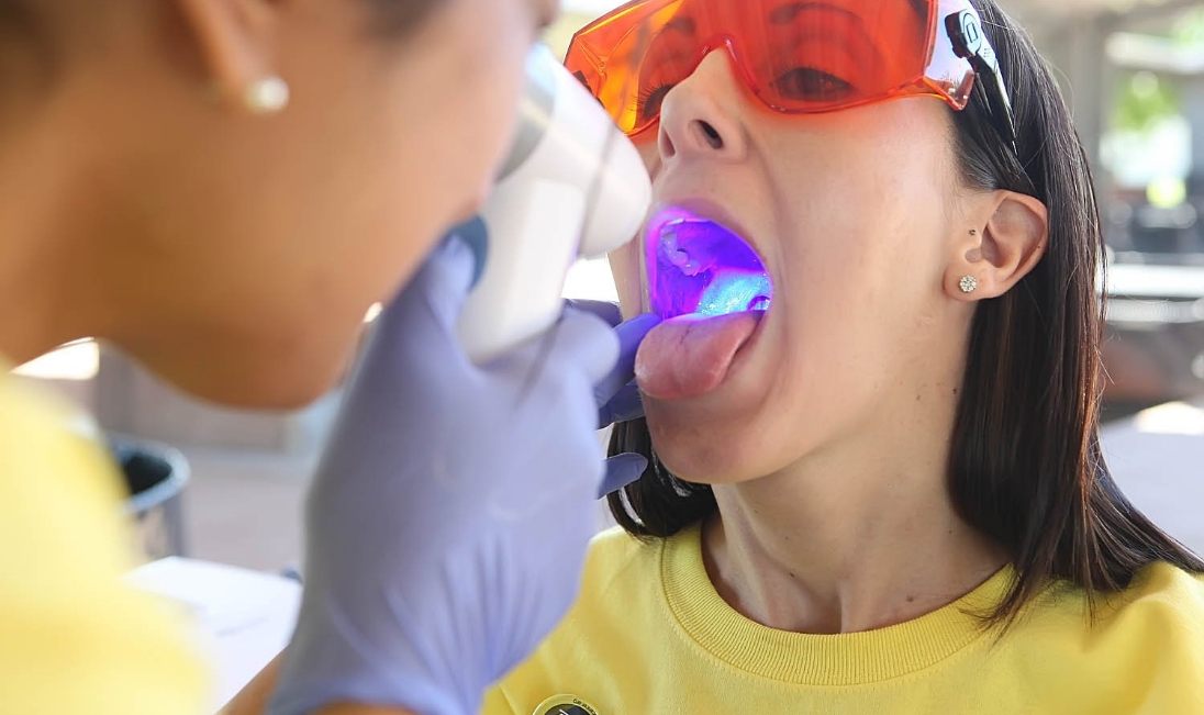 Dentist performing an oral cancer screening on a young female patient
