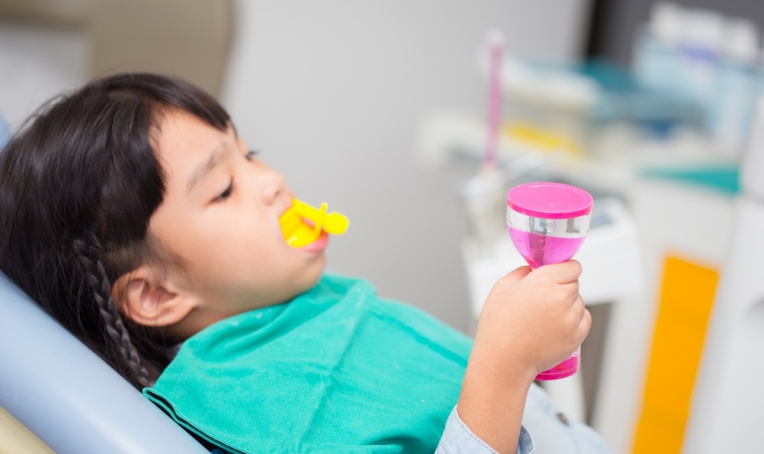 Young girl receiving a fluoride treatment in dental office