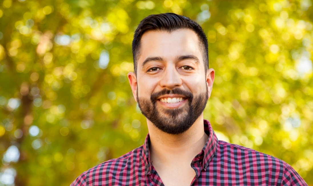 Man in red and black plaid shirt smiling outdoors