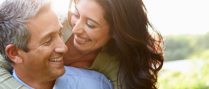 Smiling man and woman holding each other outdoors