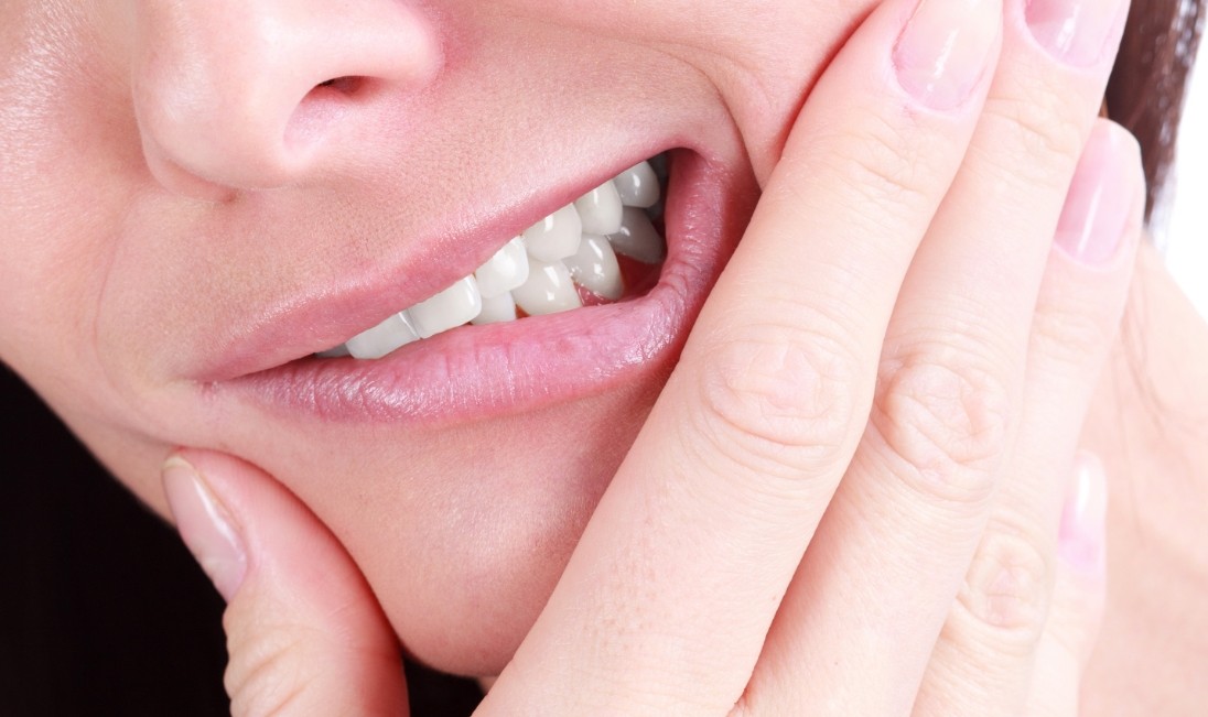 Close up of a person holding the side of their jaw in pain