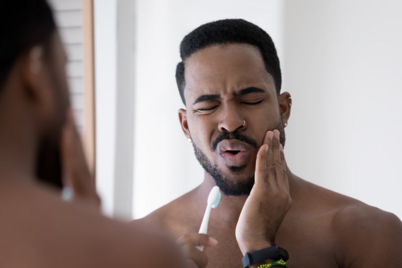 A man holding his jaw due to the pain of dry socket